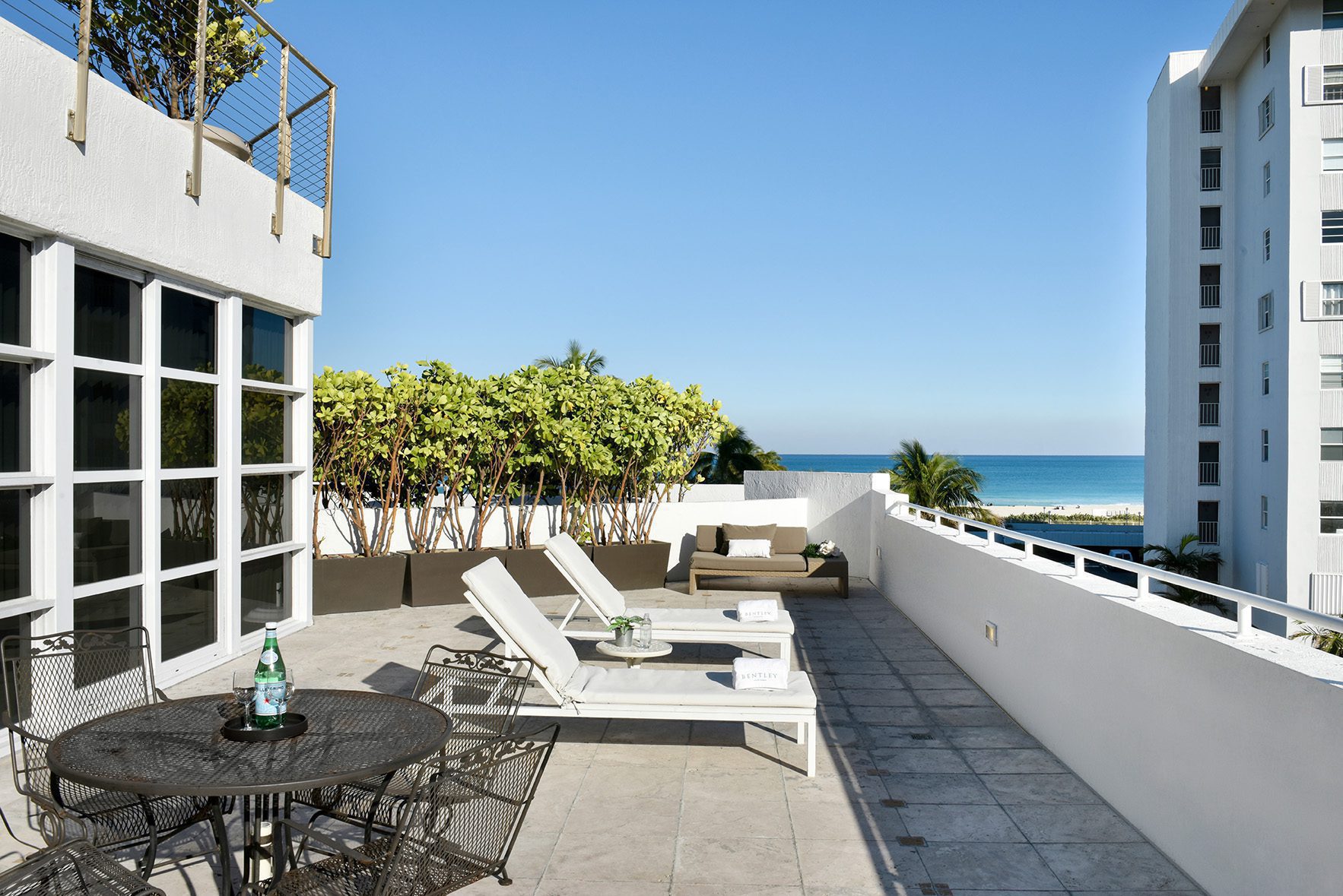 A rooftop patio with outdoor furniture and a view of the ocean.