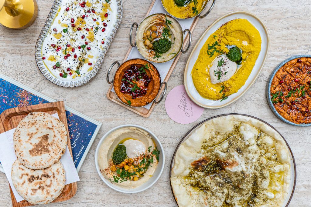 A variety of Middle Eastern dishes including hummus, flatbread, and other dips and breads.