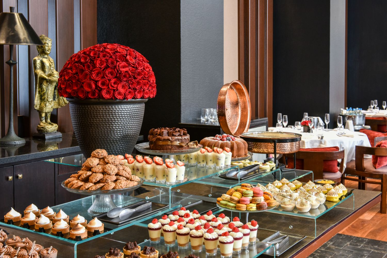 A buffet table with various desserts and a large floral arrangement